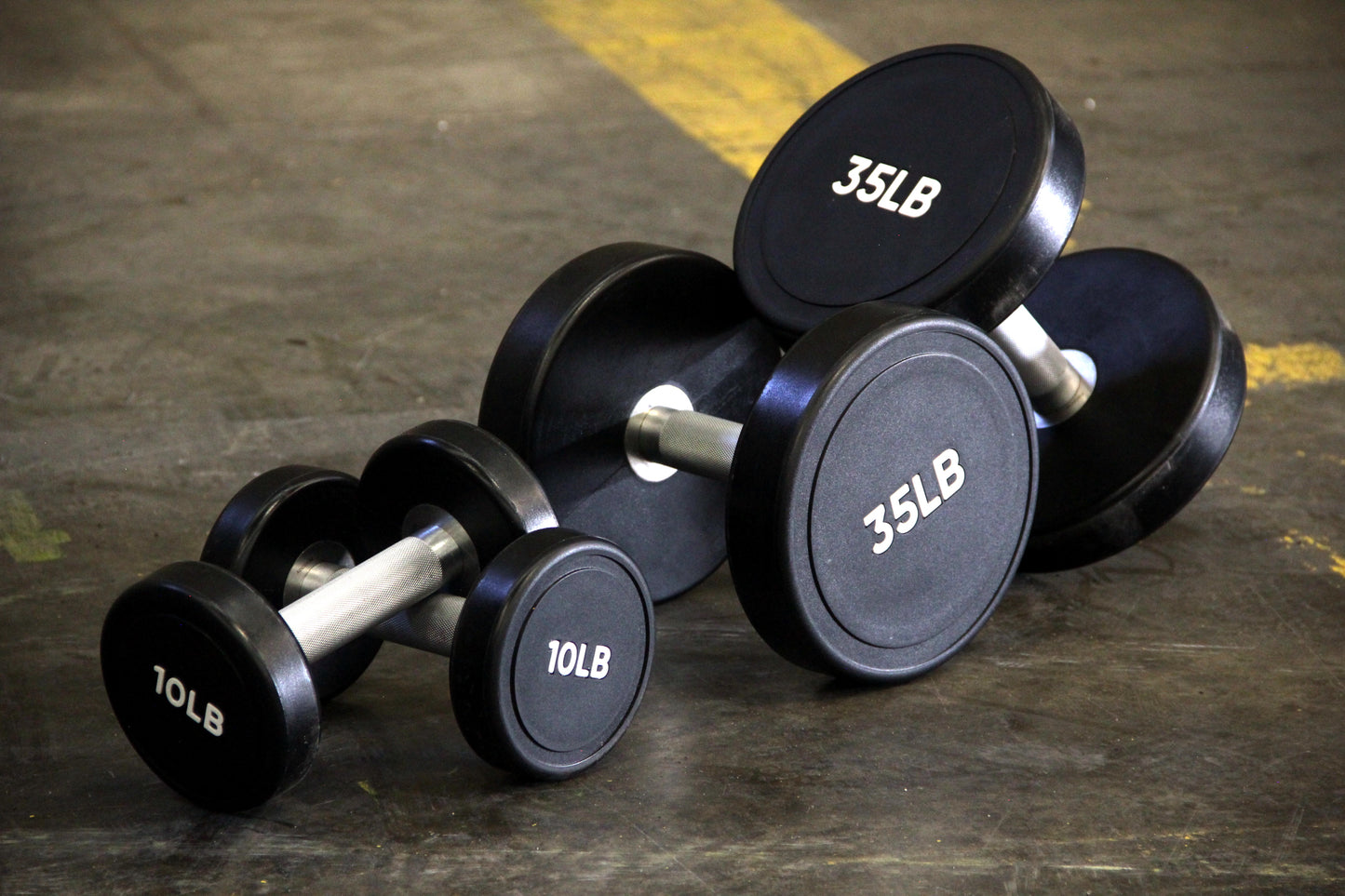 set of urethane dumbbells varying in weight, set on a gym floor