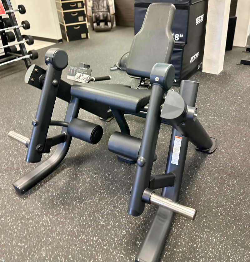 Black seated plate loaded leg extension machine in a showroom.