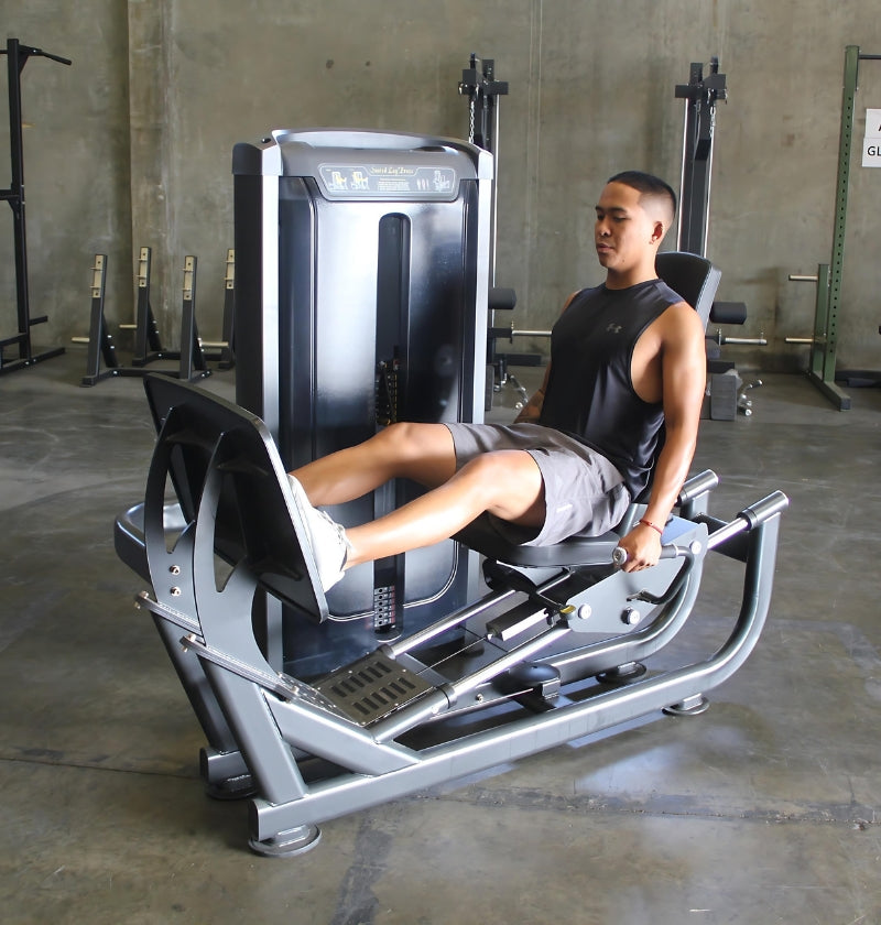 A man using a seated leg press machine in a gym, with a note stating pre-order availability in 8-10 weeks.