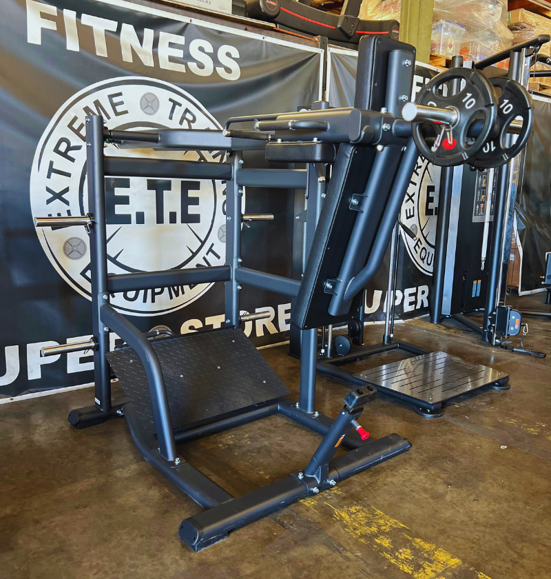 A gym setup featuring a pendulum squat machine, complete with a squat rack and bench for workout sessions