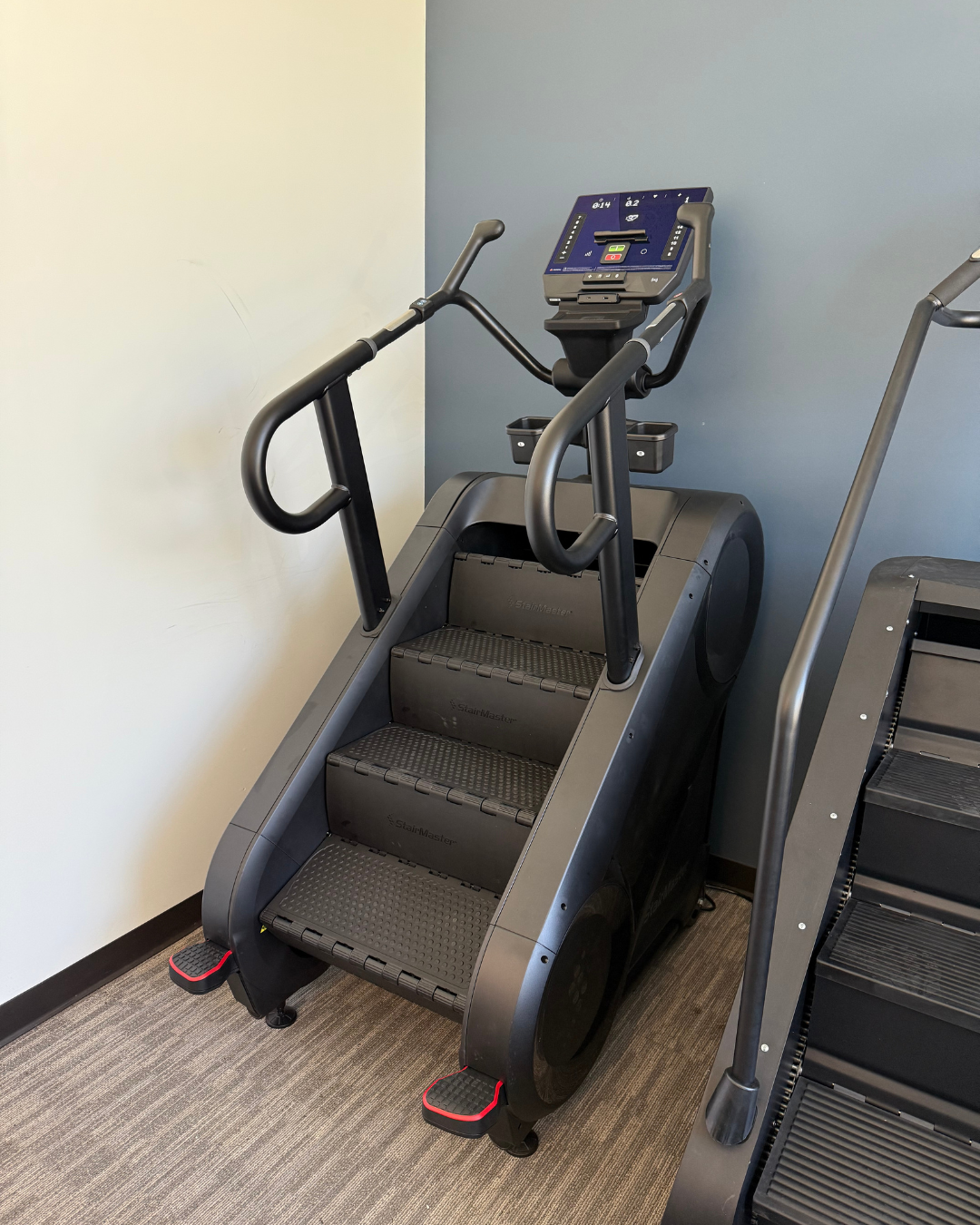 Stair climber machine in a gym setting with a neutral wall background