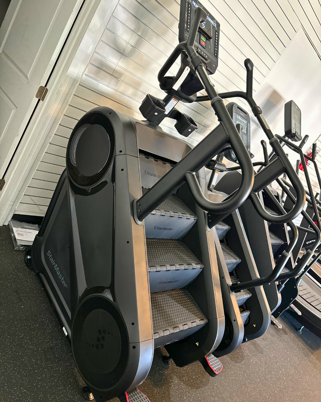 Stair climber machine in a gym setting with white walls and flooring.