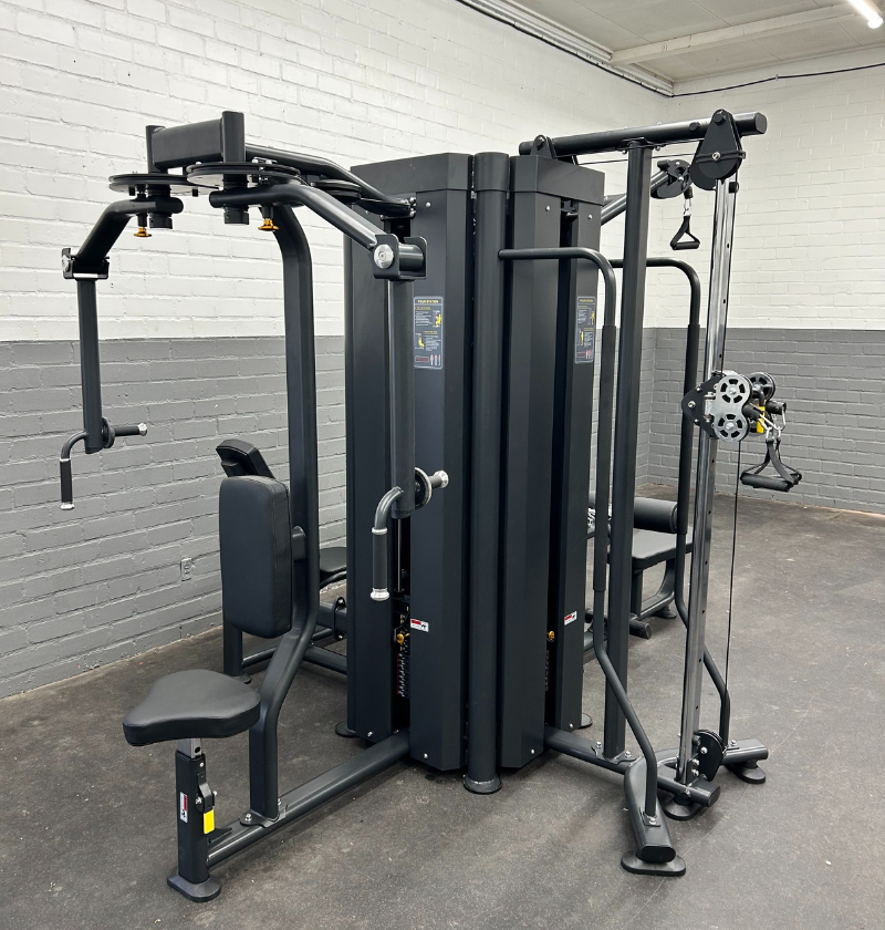 A multi functional trainer machine in a gym room with a white brick wall, providing versatile options for strength workouts.
