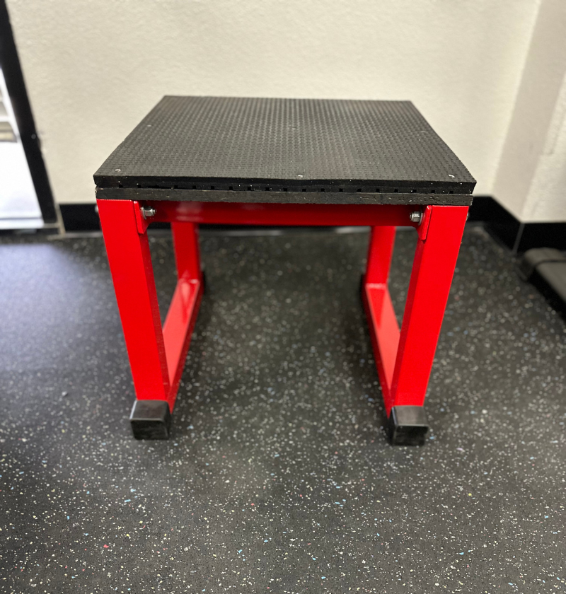 Red and black plyo box stand on a garage floor.