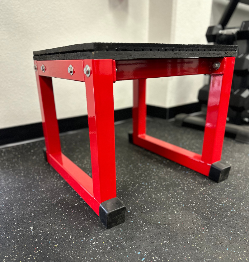 Red and black plyo box on a gym floor.