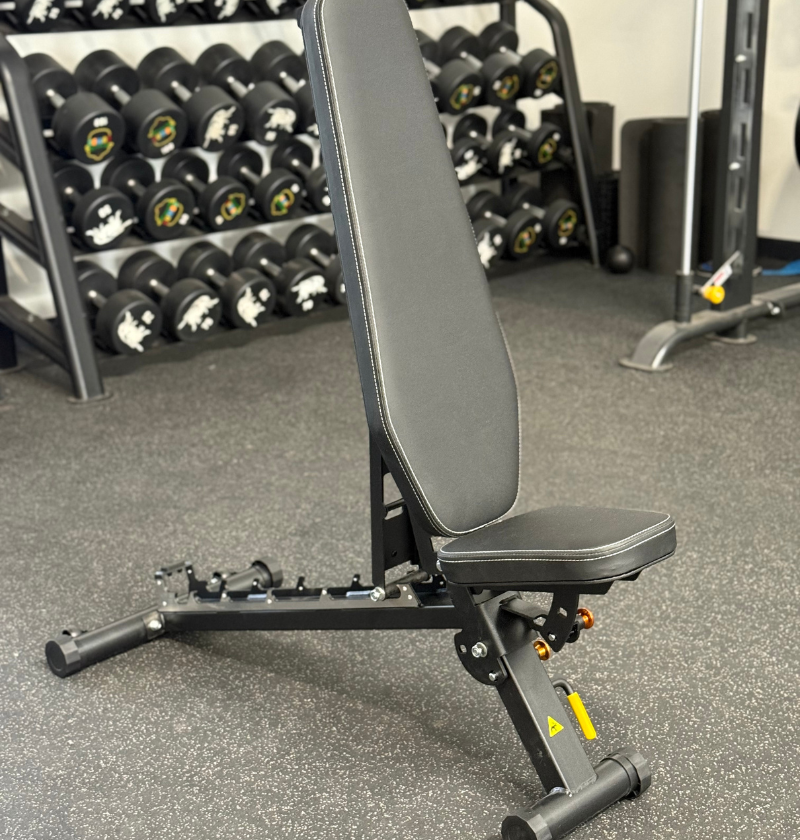 Black foldable flat incline bench in a gym setting.