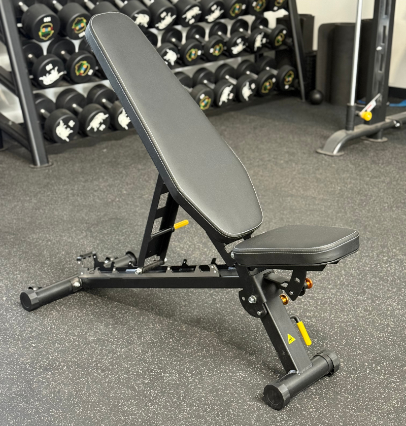 foldable incline bench in gym setting with dumbbells in the background