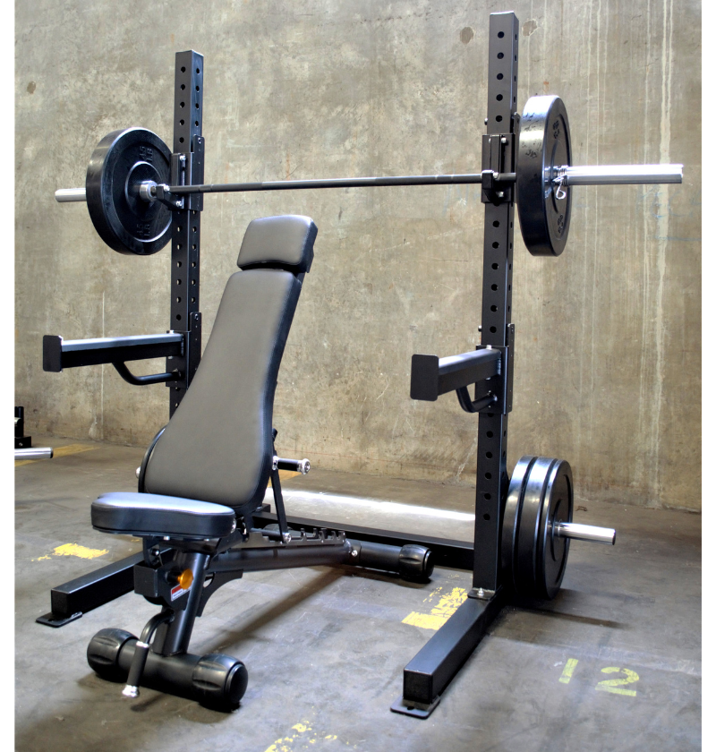 A black 6ft Basic Squat Rack with a pair of spotter arms, j-hooks, and weight peg holders, accompanied by a power bar and an adjustable bench.