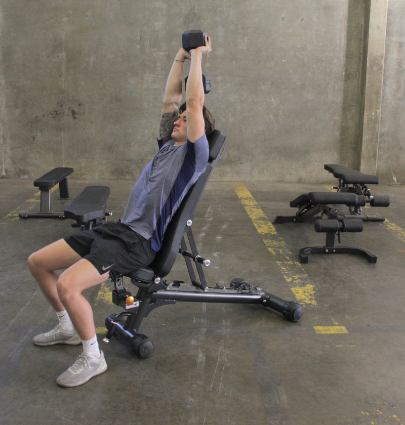 A man is exercising on the Adjustable Flat Incline Bench ELITE PL7328B, showcasing a fitness routine for strength training.