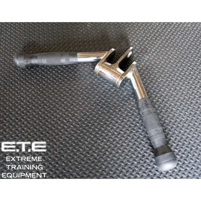A pair of metal hand grips for a tricep press down attachment on a black surface.