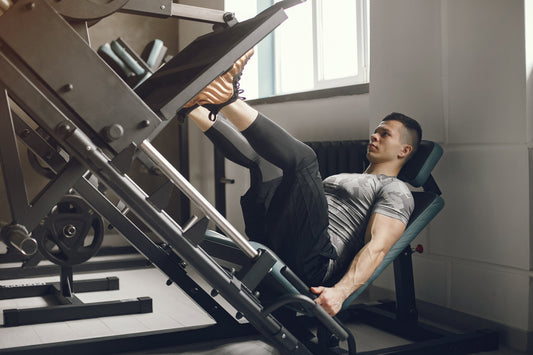 A man using a leg press machine for leg exercises in a well-equipped home gym.