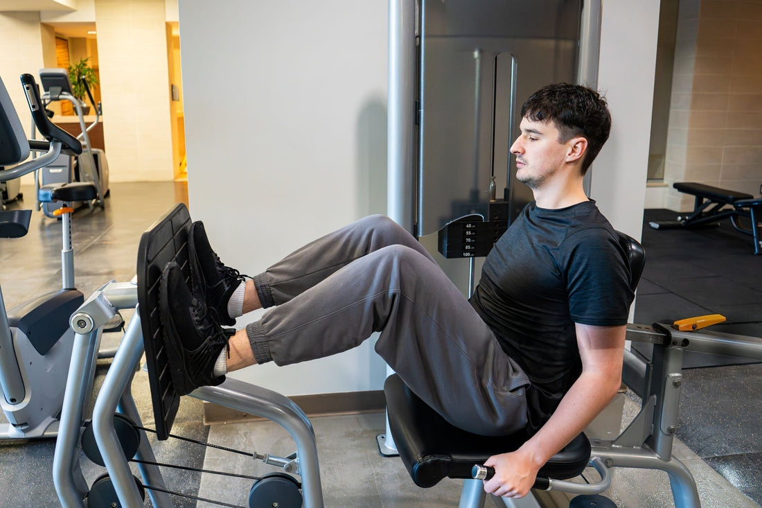 A man pedals on a stationary bike in a gym, surrounded by various workout machines and equipment.