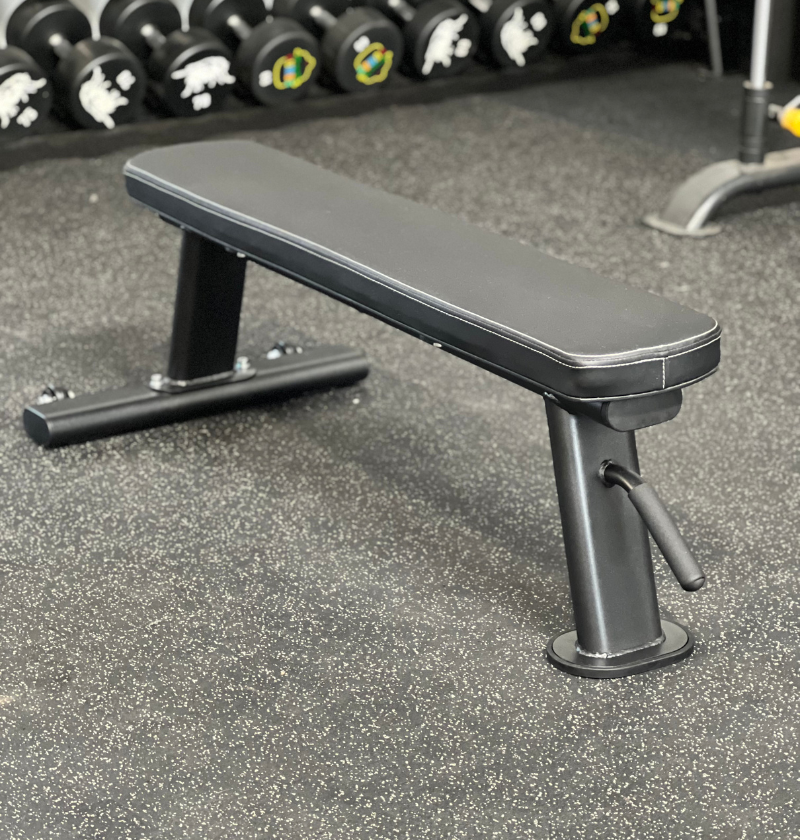 A black bench positioned in front of a horizontal bar, suitable for exercise or outdoor seating.