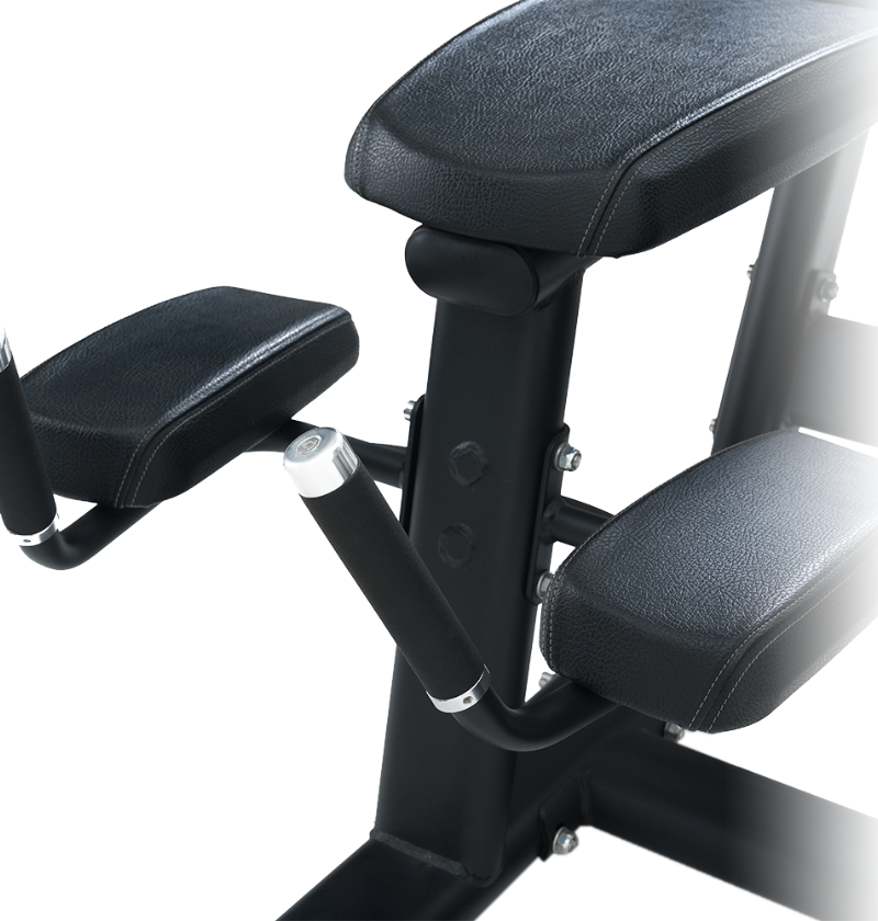 Close-up of a black prone leg curl machine with arm pads and handle on a white background