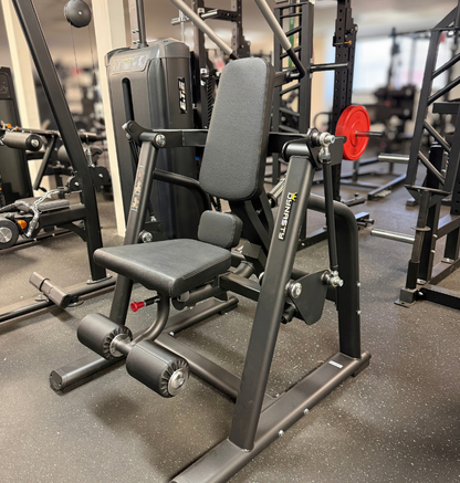 A black plate loaded ab crunch gym machine in a fitness center setting.
