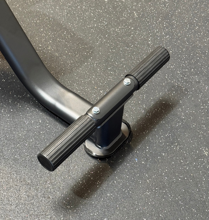 Up-close photo of the footrest on a black tricep seat on speckled flooring