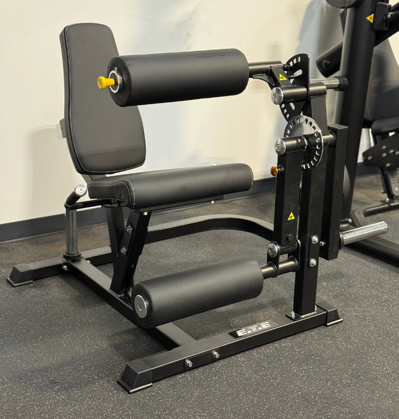 Black plate loaded leg extension leg curl in a gym setting.
