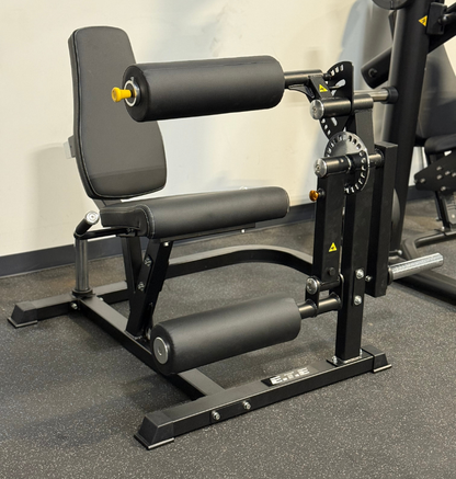 Black plate loaded leg extension leg curl in a gym setting.