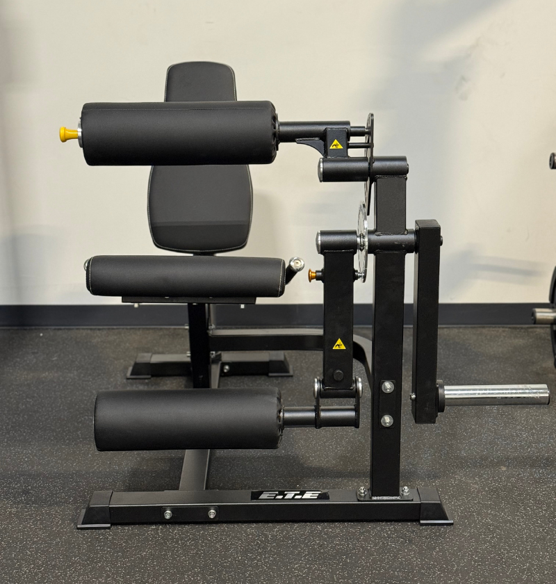 Black plate loaded leg extension leg curl machine in a gym setting.