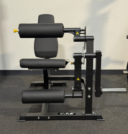 Black plate loaded leg extension leg curl machine in a gym setting.