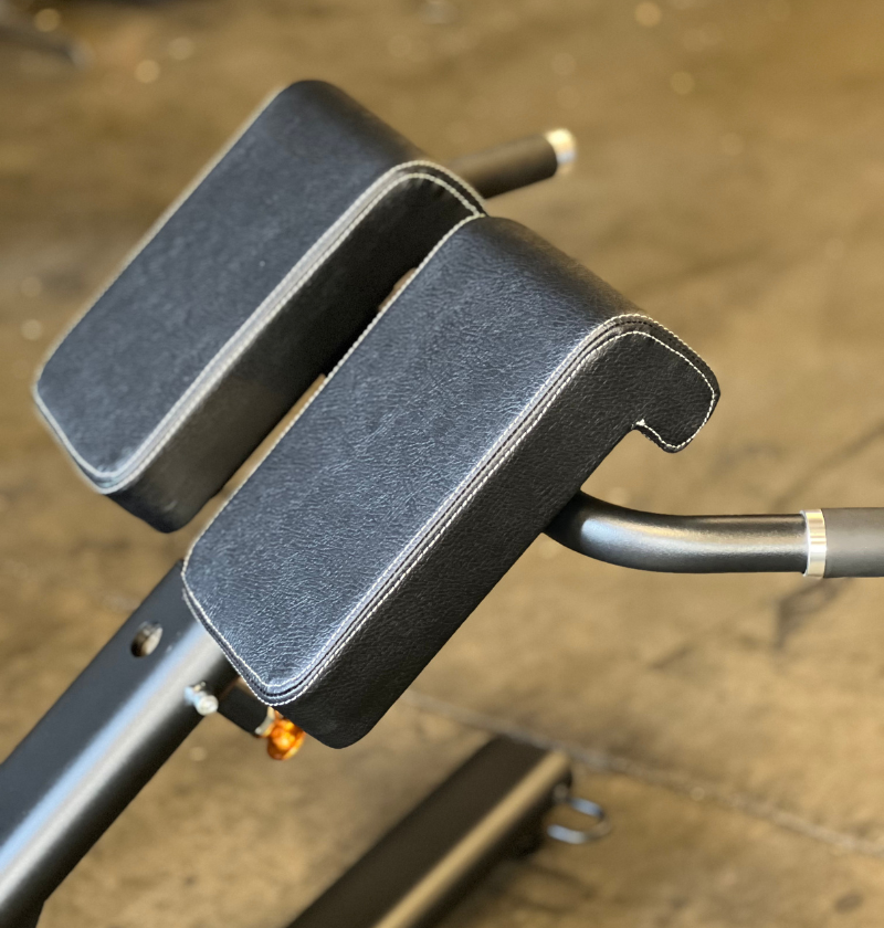 Close-up of black pads on a 45 degree hyperextension on a concrete floor.