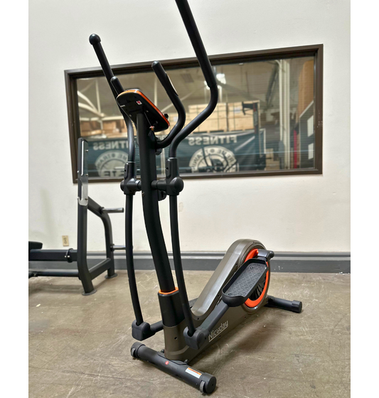 Elliptical machine in a gym setting with a mirror reflecting gym equipment.