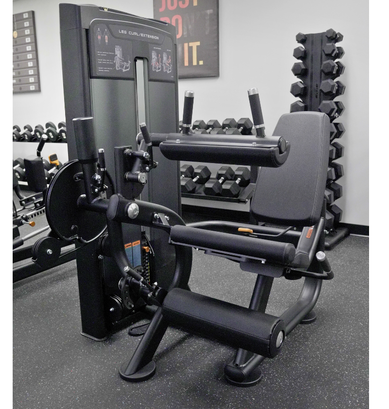 Leg extension leg curl Gym machine in a fitness showroom with weights and equipment in the background