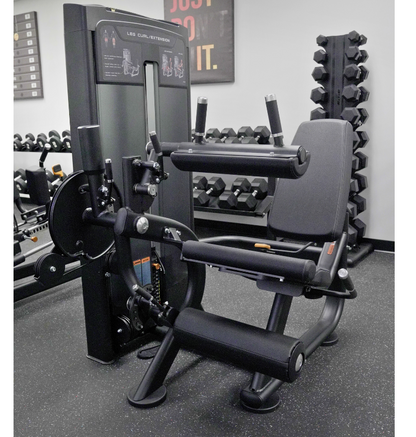 Leg extension leg curl Gym machine in a fitness showroom with weights and equipment in the background