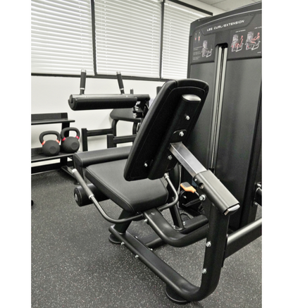 Leg extension leg curl Gym machine in a fitness showroom with weights and equipment in the background